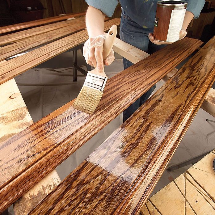 Brushing on a layer of finish onto a piece of trim | Construction Pro Tips