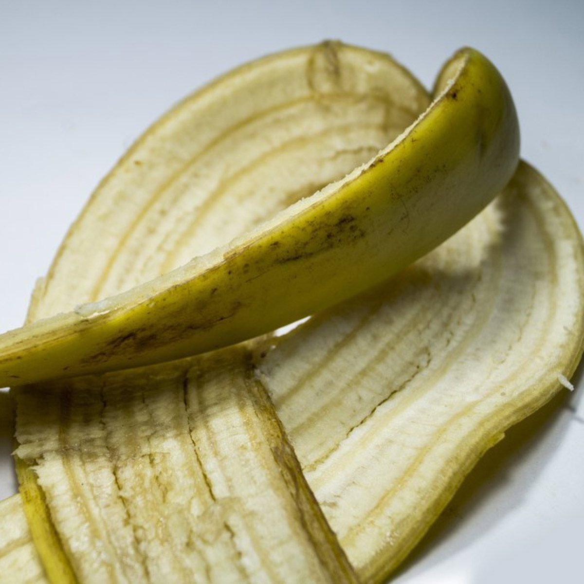 A peeled banana skin lies on a flat surface, showcasing its yellowish interior and light brown streaks, suggesting recent peeling.