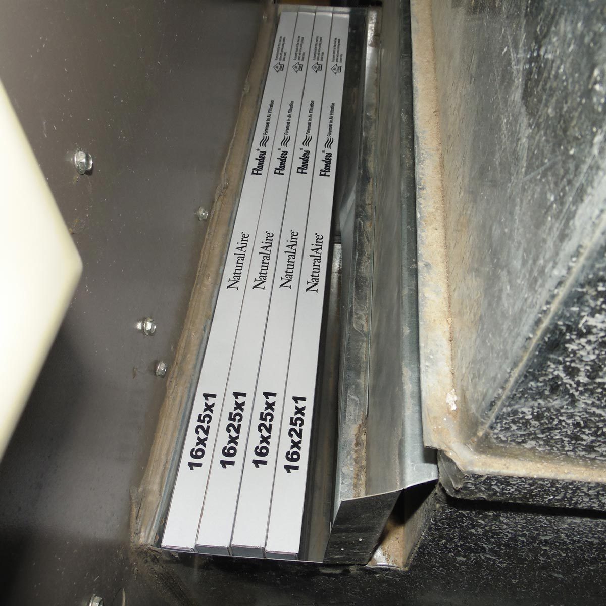 Metal filter frames are stacked inside a duct. They are labeled with dimensions "16x25x1," suggesting use in an air filtration system.