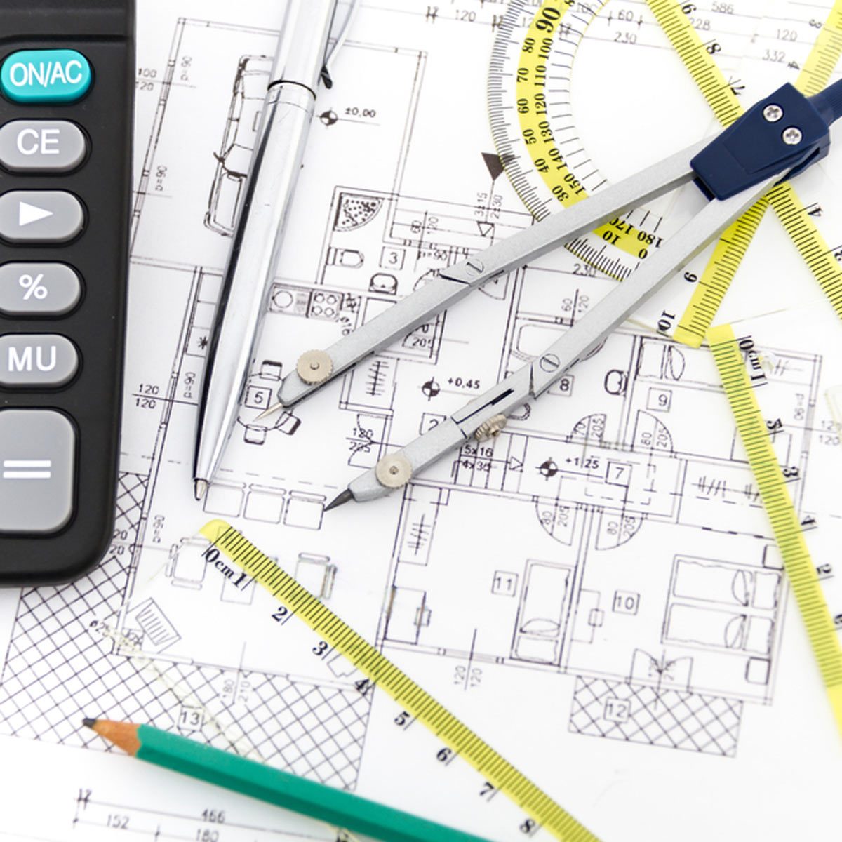 A set of drafting tools, including a compass and pens, is positioned over architectural blueprints on a desk, suggesting design or planning activities.
