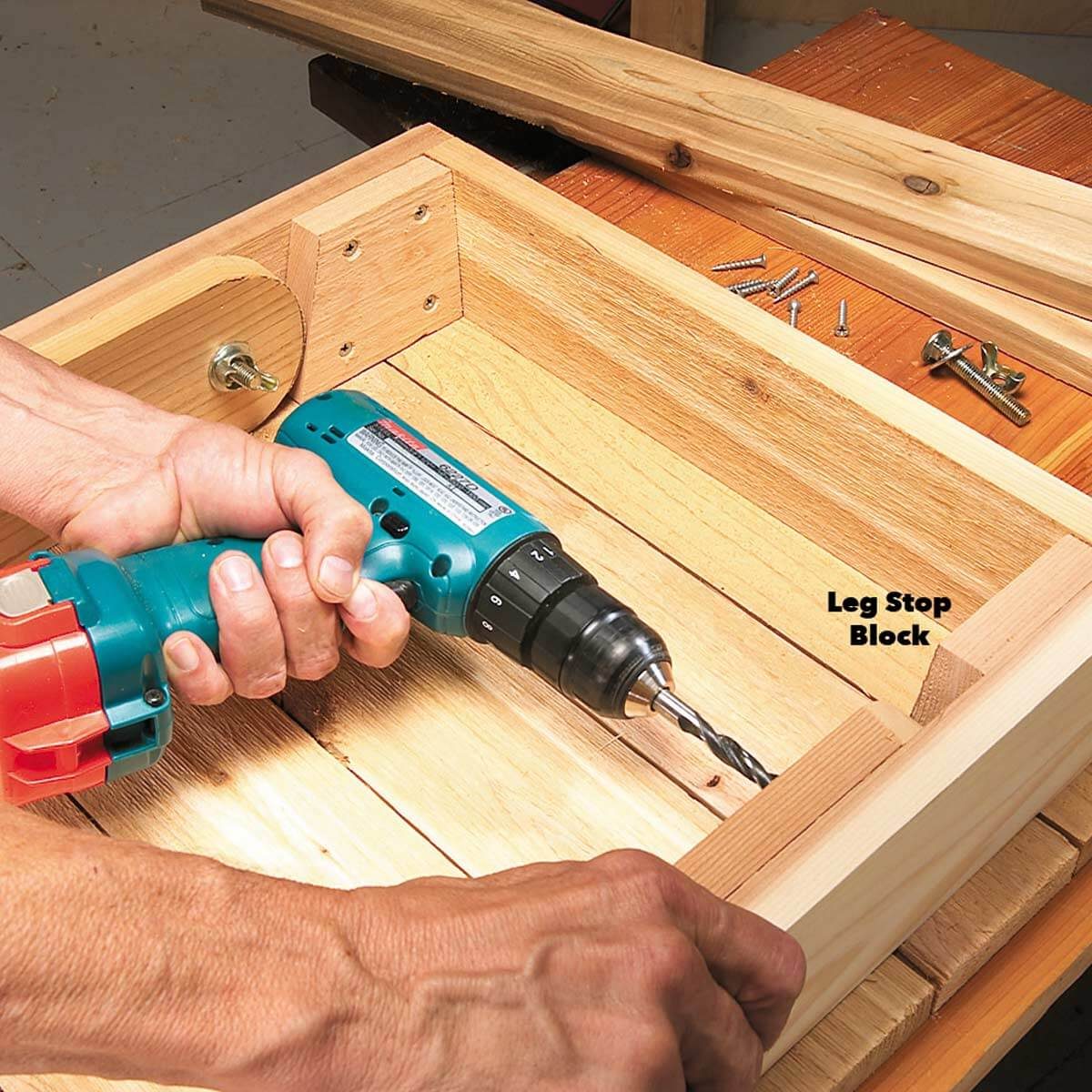 A person uses a handheld drill to create holes in wooden pieces, positioned on a work surface with screws and tools nearby.