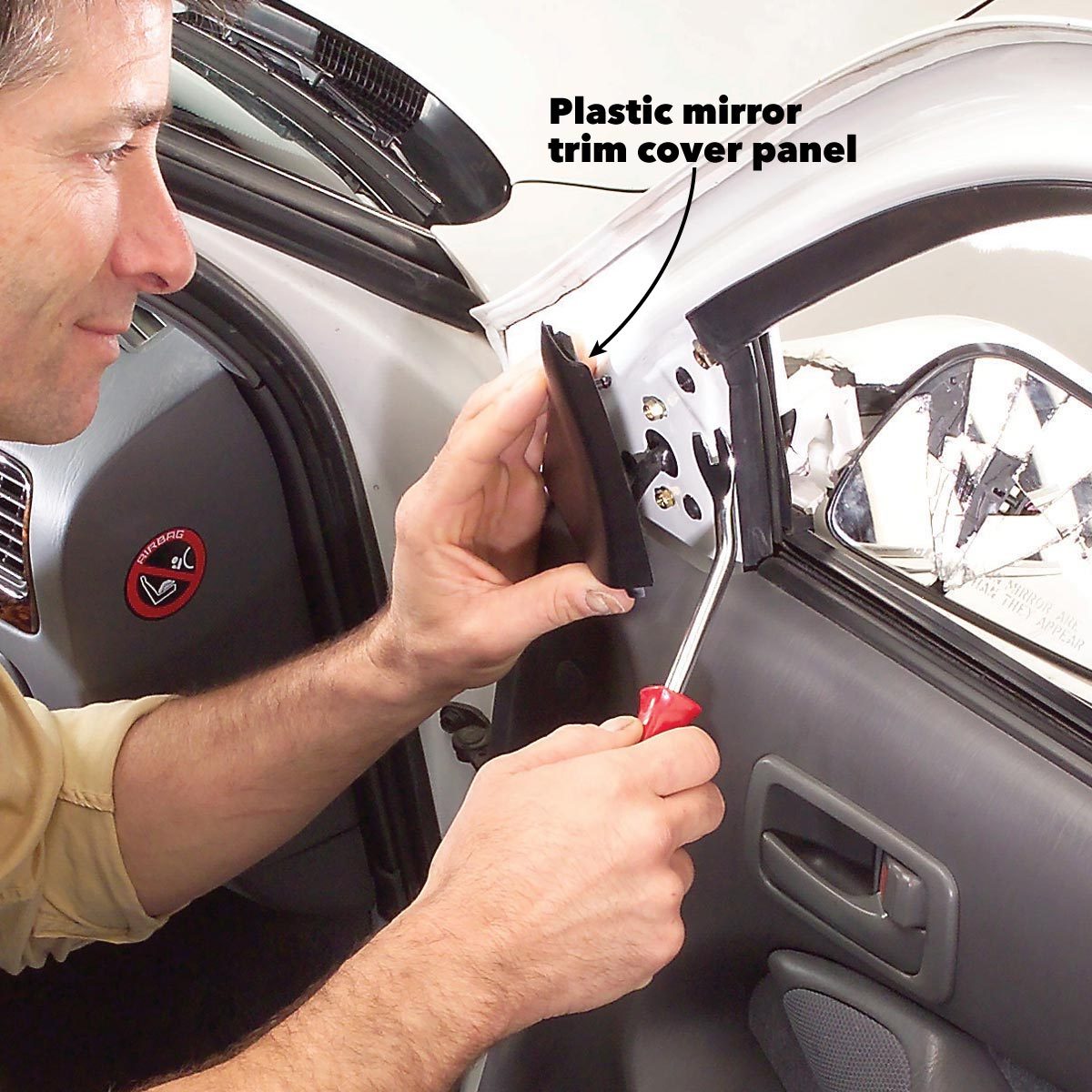 A person is installing a plastic mirror trim cover panel on a car's door, using a screwdriver in an automotive interior setting.