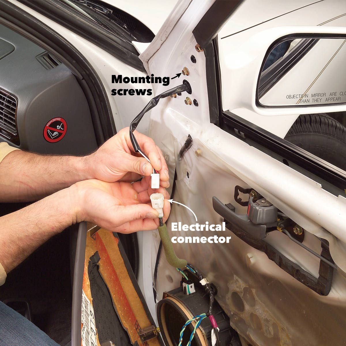 A person is connecting an electrical connector inside a car door, with mounting screws visible in the background. The environment is a vehicle interior.