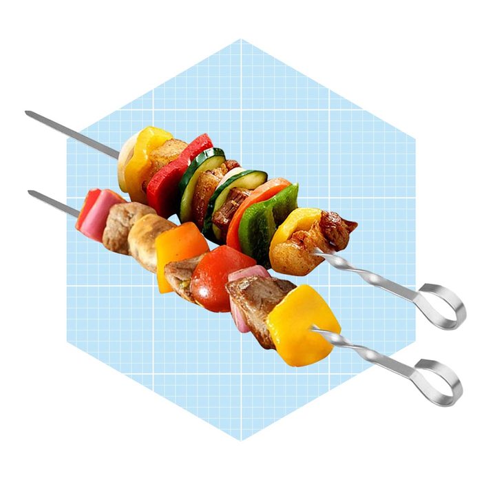 Two skewers layered with colorful vegetables and meat are displayed against a light blue grid background.