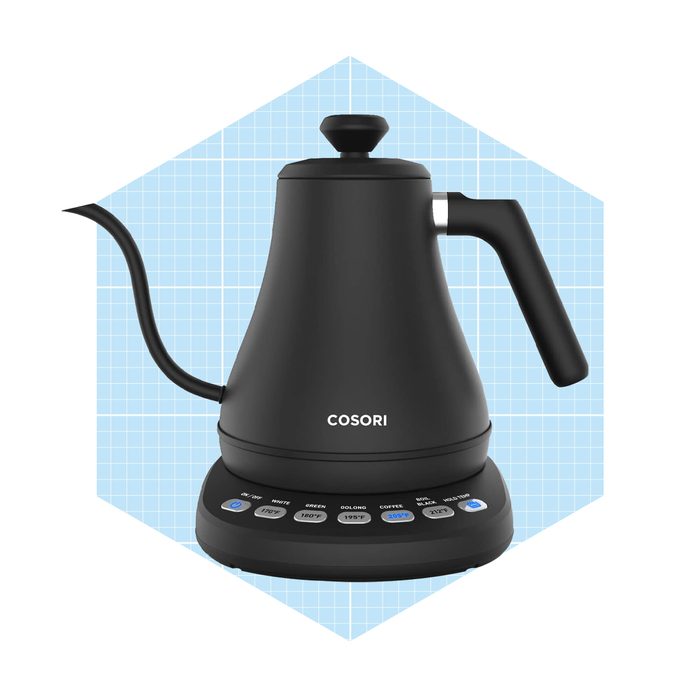 A black electric kettle sits on a base, with buttons for temperature settings, against a light blue grid background.