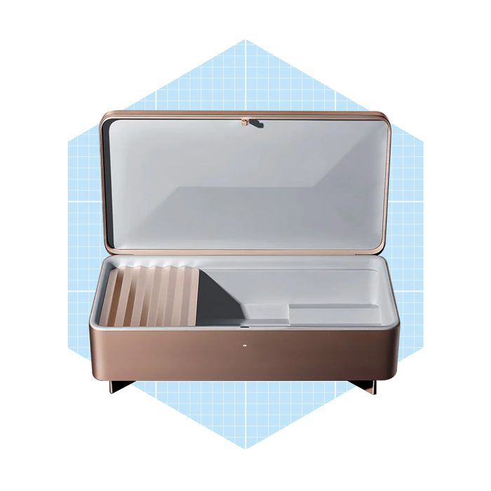 A sleek, open storage container reveals organized compartments, showcasing a modern design against a light blue grid background.