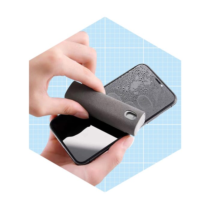 A hand uses a gray cleaning tool to wipe a smartphone screen, removing water droplets, against a light blue grid background.