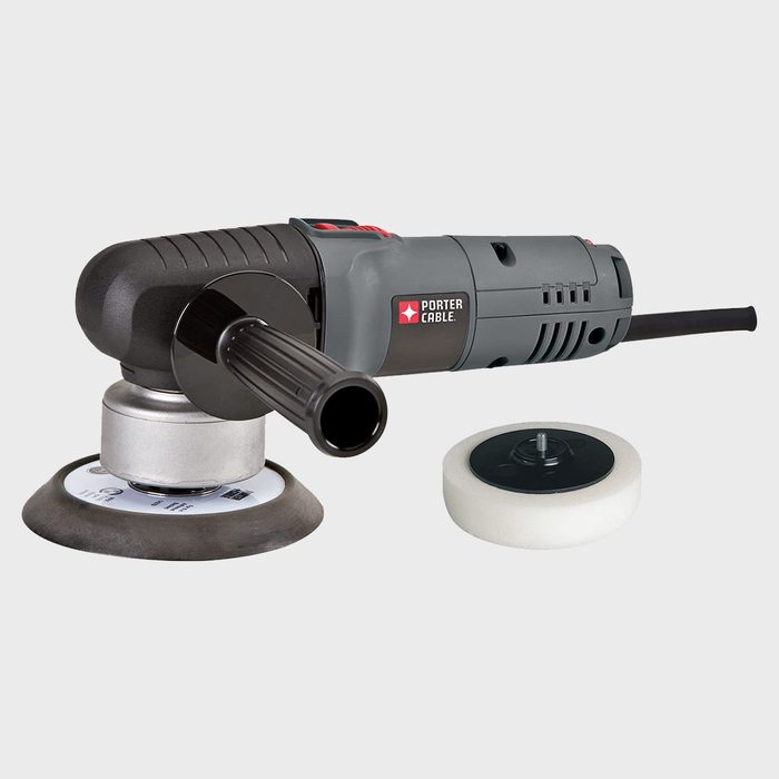 A power sander is positioned with a polishing pad attached, ready for use on surfaces, accompanied by an additional foam pad on a plain background.