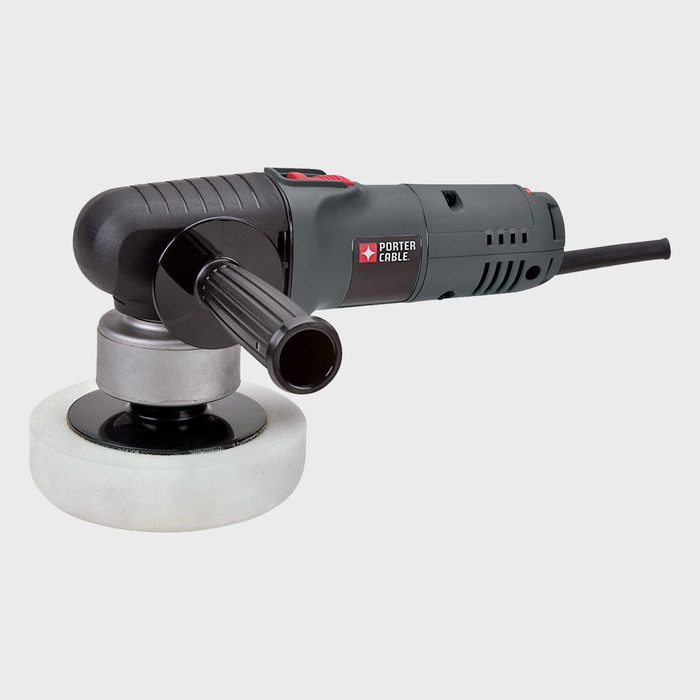 A power sander with a round pad is resting, ready for use. It features a handle and a power cord, set against a plain background.