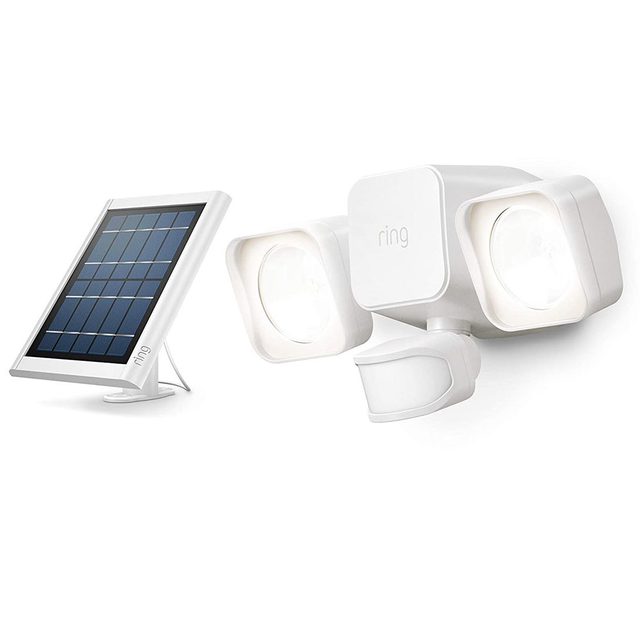 A white motion-activated security light with dual bright bulbs and a sensor is positioned beside a solar panel, designed for outdoor installation.