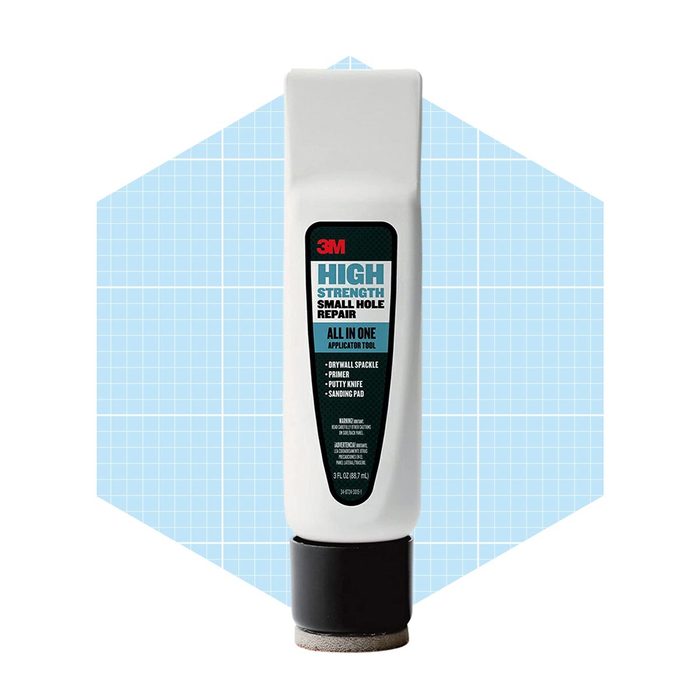 A white applicator tool stands upright, labeled for high-strength small hole repair, featuring an integrated putty knife, primer, and sanding pad, against a blue grid background.