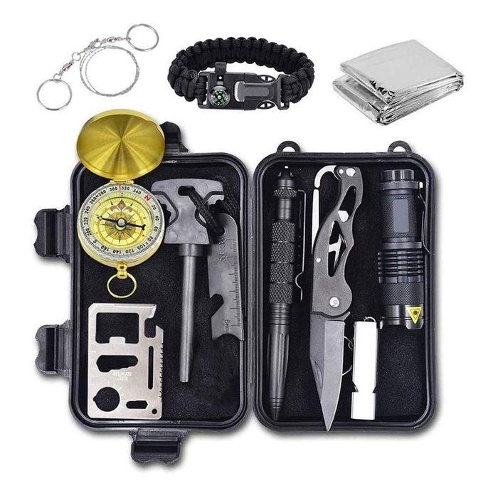 A compact survival kit contains tools like a compass, knife, flashlight, and multi-tool, arranged in a protective case with extra survival gear nearby.