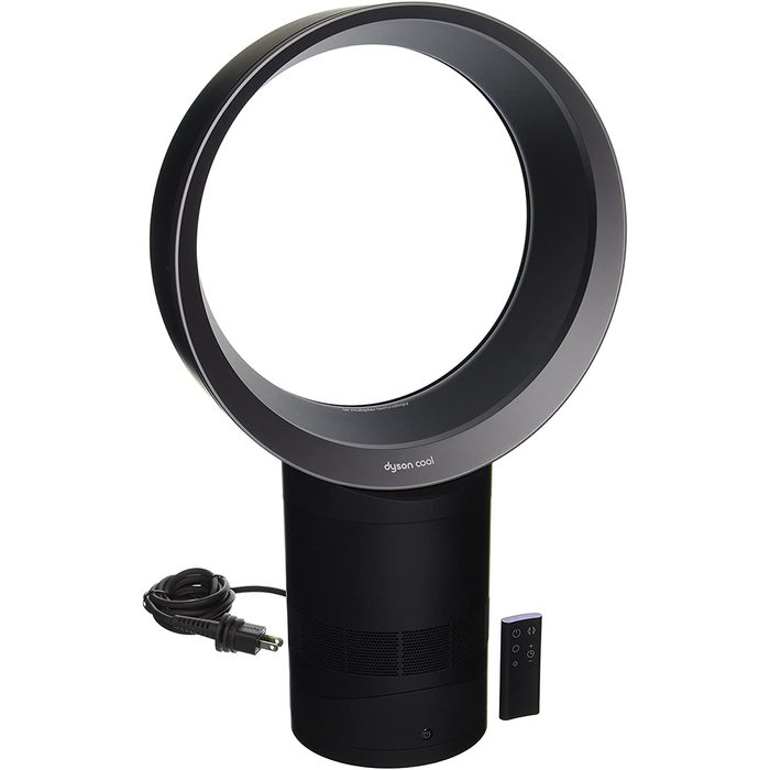 A circular fan blows air while standing on a cylindrical base. A power cord and remote control are present, indicating usability in various settings.