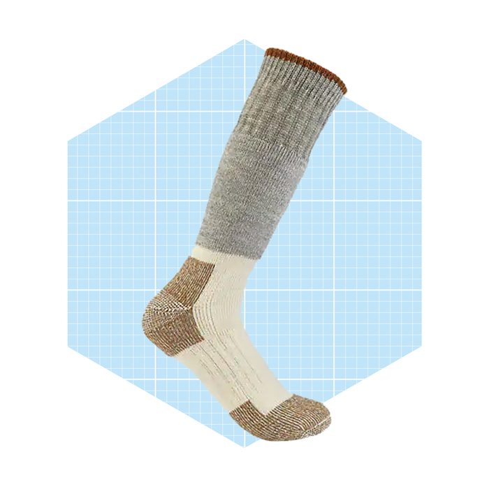 A gray and cream sock is tilted upward, showcasing its ribbed band and reinforced toe, placed against a light blue geometric background.
