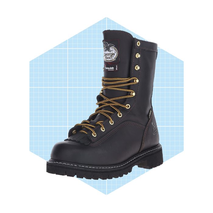 A sturdy black boot with golden laces stands prominently against a light blue grid background, showcasing its rugged design and supportive features.