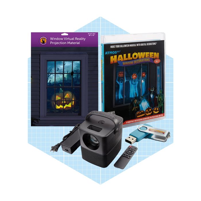 A projector displays a Halloween scene, surrounded by a DVD, USB stick, and a window projection material, all designed for festive decorations.