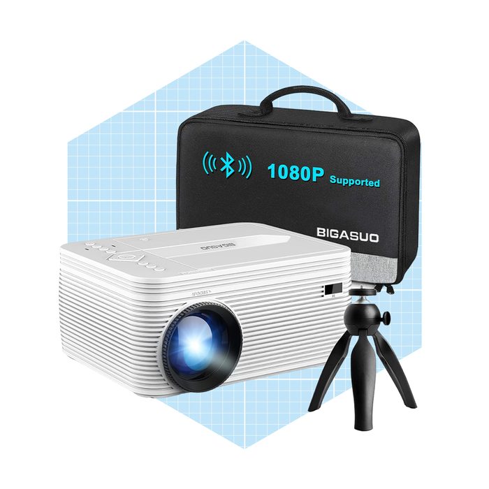 A white projector projects light, positioned on a tripod next to a black carrying case marked 