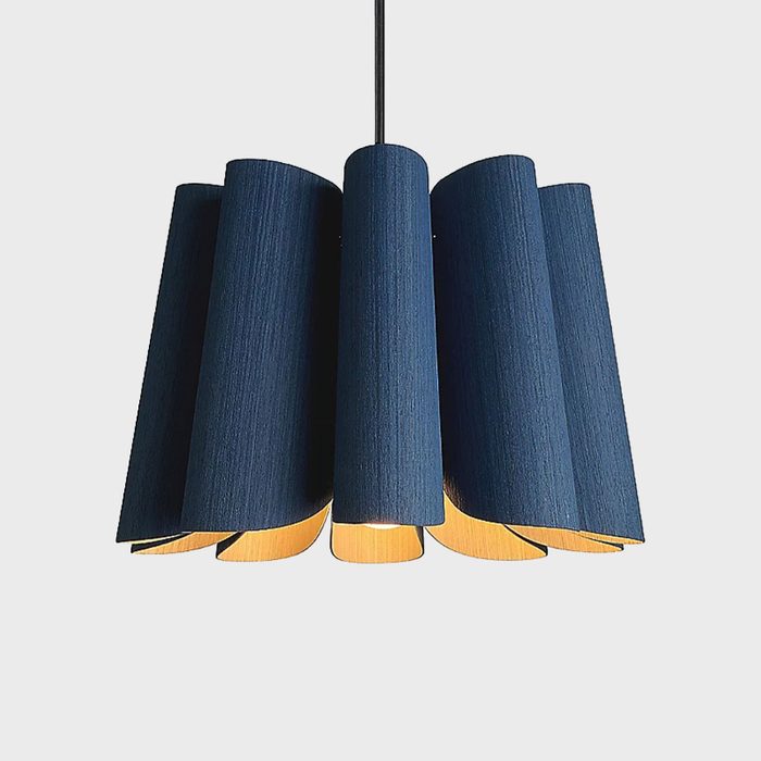 A pendant lamp with curved, blue fabric shades illuminates from within, suspended by a black cord against a light gray background.