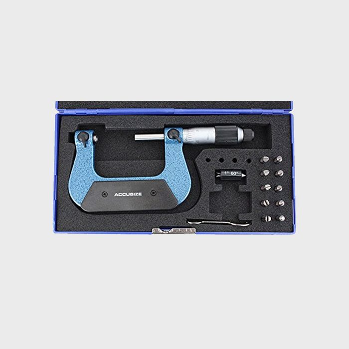 A blue micrometer measuring tool sits in a foam-lined case, accompanied by various attachments and calibration standards for precise measurements.