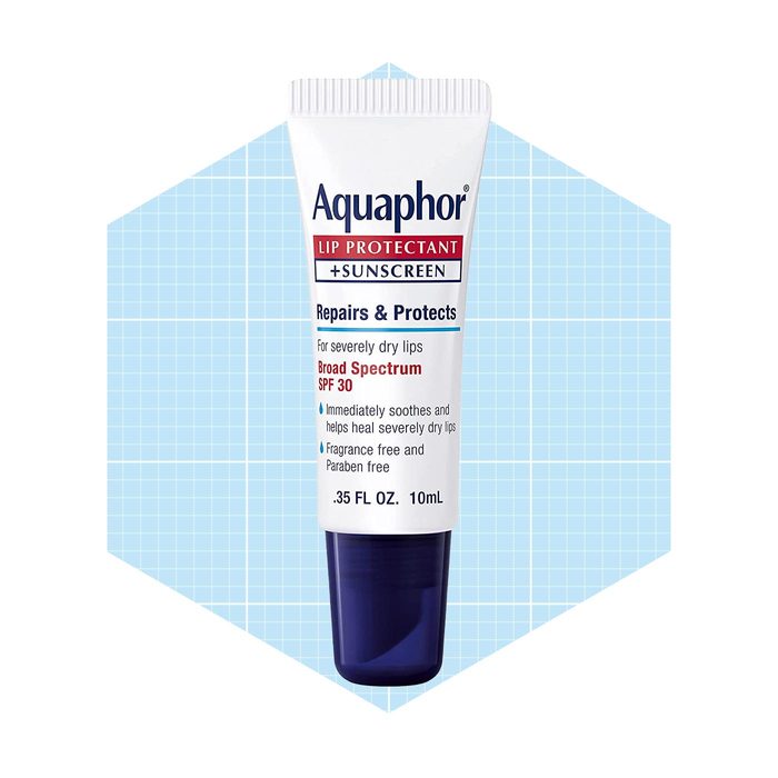 A tube of Aquaphor lip protectant sits against a light blue grid background, promoting its moisturizing and protective properties with an SPF 30 label.