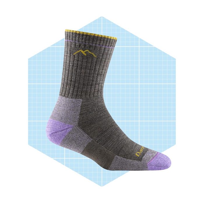 A gray sock with purple accents stands upright, showcasing its design against a light blue grid background, emphasizing its outdoor functionality and durability.