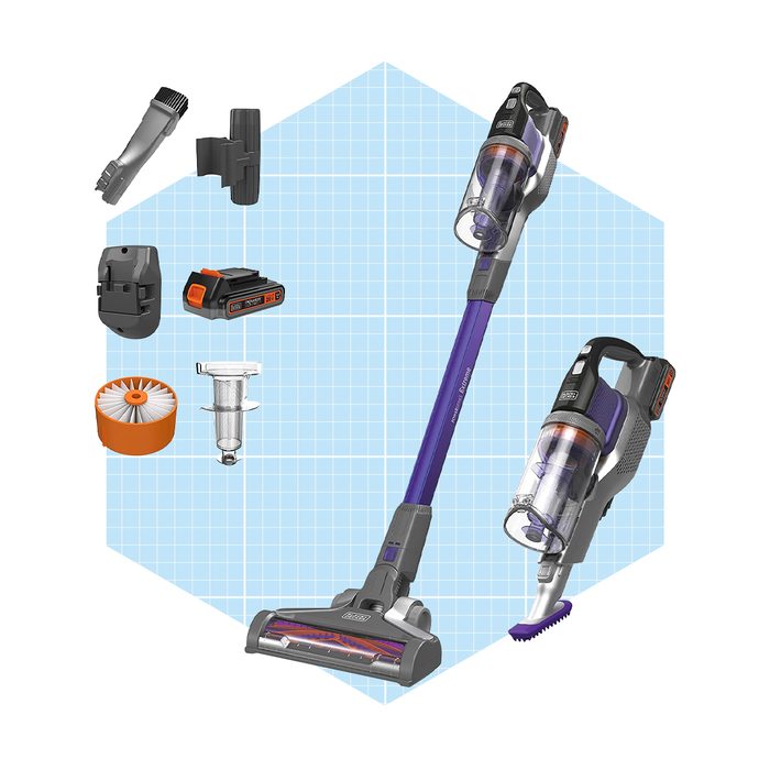 A cordless vacuum cleaner with various attachments rests against a light blue grid background, ready for cleaning tasks in a home environment.