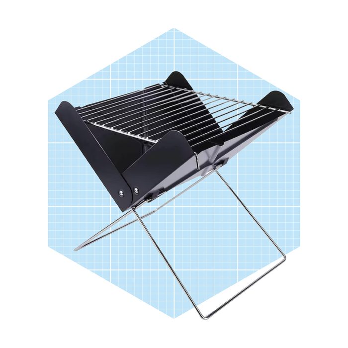 A portable charcoal grill stands upright, with a metal grate on top, set against a light blue grid background, suggesting outdoor cooking.