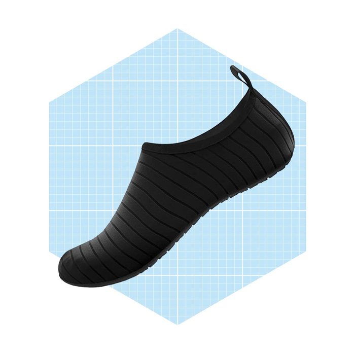 A black slip-on shoe features a textured surface and a flexible sole, positioned against a light blue grid background within a hexagonal shape.