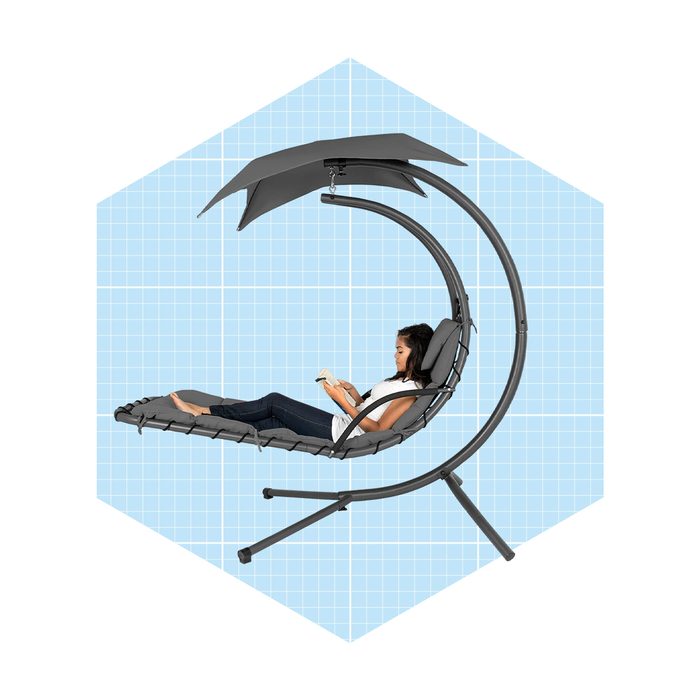 A woman relaxes on a curved outdoor lounge chair, reading a book, beneath an adjustable shaded canopy against a light blue geometric background.