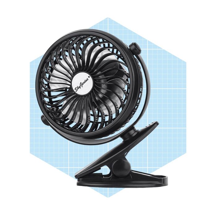 A compact black fan circulates air, mounted on a clip, set against a light blue grid background.