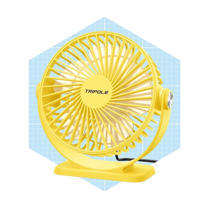 A yellow table fan spins, providing airflow in a light blue geometric background, ideal for cooling in warm environments.