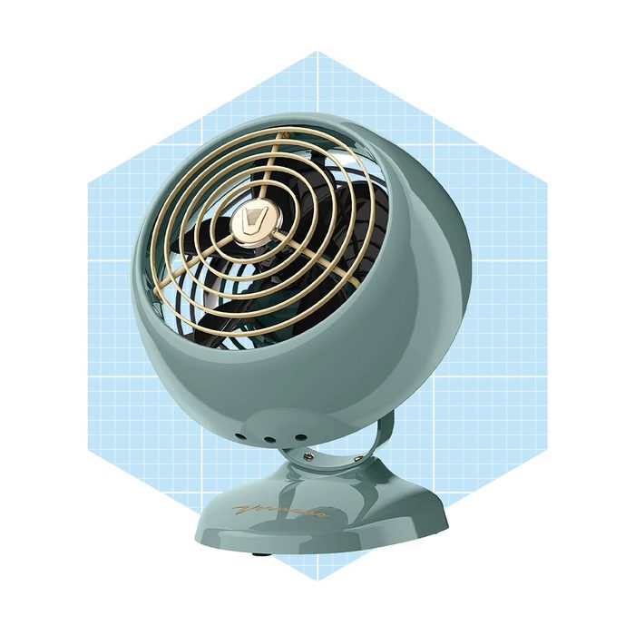 A vintage-style tabletop fan circulates air, featuring a rounded body and gold accents, set against a light blue geometric background.
