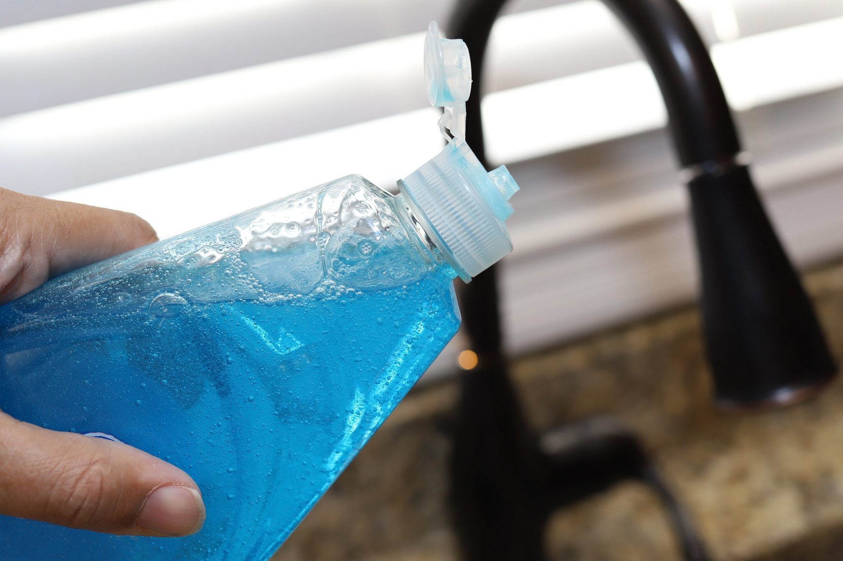 A woman holding a bottle of dish detergent in her hand