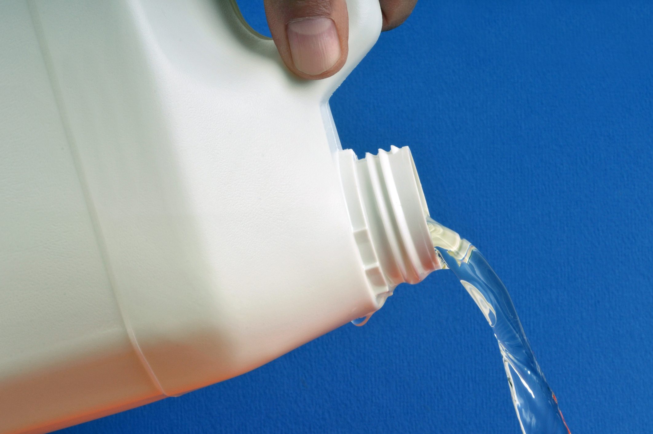 Carton of bleach pouring out in front of a blue background